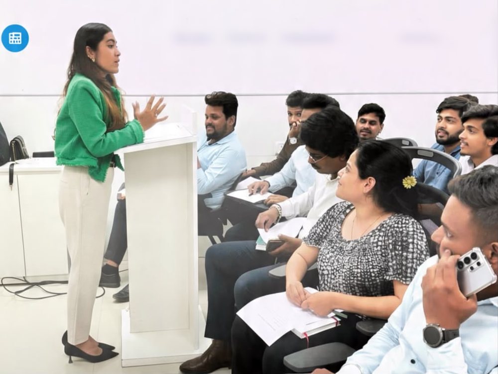A therapist leading a mental health awareness session for a seated audience in a lecture room.
